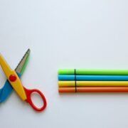 Multicolored scissor and four coloring pen on white surface