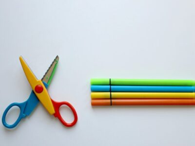 Multicolored scissor and four coloring pen on white surface