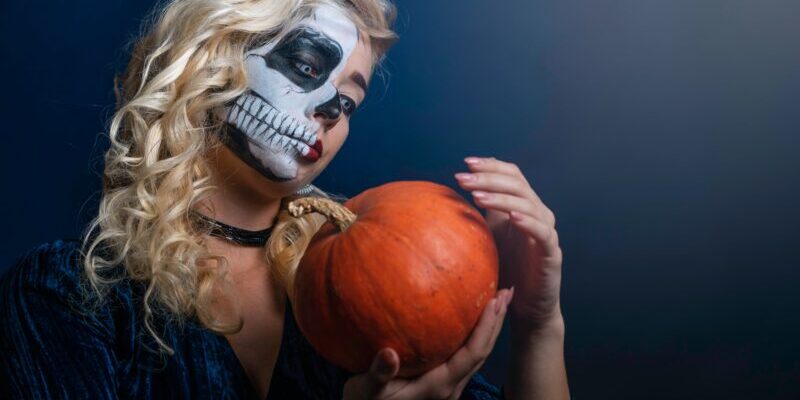 Woman with face paint with pumpkin